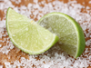 Two lime wedges on a bed of salt with a wooden background