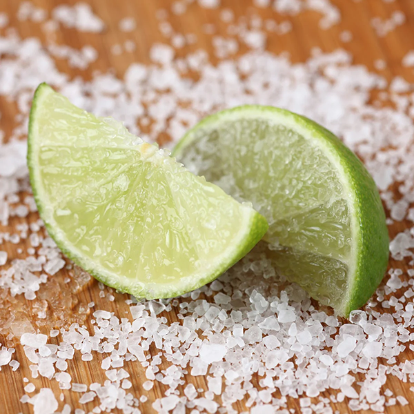 Two lime wedges on a bed of salt with a wooden background