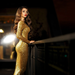 Woman in a gold sequin dress standing against a dark background