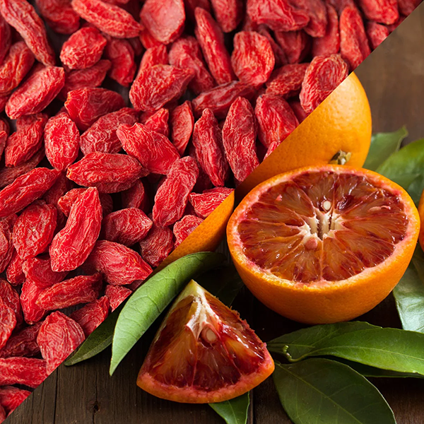 Goji berries and blood oranges on a wooden surface with green leaves.