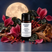 Moonlit Night fragrance oil bottle with deep pink flowers, patterned leaves, red berries, wood and amber-coloured chunks beneath a full moon.