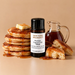 New York Breakfast fragrance oil bottle with butter-topped pancakes, a jug of syrup and golden cake pieces.