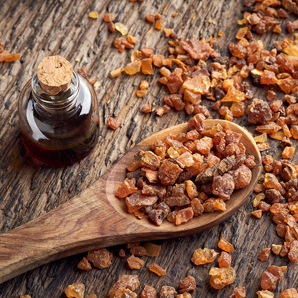 Bottle of resin and wooden spoon filled with resin on a wooden surface