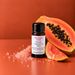 Pink Papaya Sugar fragrance oil bottle with a halved papaya with black seeds, a papaya wedge and pink sugar crystals.