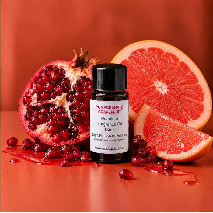 Pomegranate Grapefruit fragrance oil bottle with a pomegranate half, pink grapefruit slices and scattered pomegranate seeds.