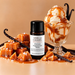 Vanilla Caramel New Formula fragrance oil bottle with caramel-drizzled ice cream in a glass dish, caramel cubes and vanilla pods.