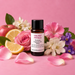 Velvet Petals fragrance oil bottle with a pink rose, pink and purple flowers, white blossoms, apple, lemon slices and rose petals.